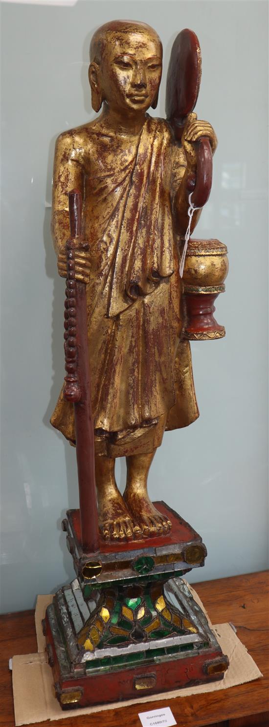 A Tibetan carved giltwood figure of a monk on mirrored plinth base